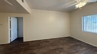 Located at 13621 W Glendale Ave in Glendale, AZ, this 670 sq ft single-floor unit offers 2 bedrooms and 1 bathroom with a consistent, clean aesthetic throughout. Dark hardwood-style flooring runs through every room, providing a cohesive and modern look. The kitchen features light wood cabinetry, white countertops, a built-in dishwasher, an electric range, and a full-size refrigerator. A convenient in-unit laundry closet is tucked adjacent to the kitchen, housing a full washer and dryer. The primary bedroom measures 140 sq ft and includes a ceiling fan, a window for natural light, and a mirrored sliding closet door. The second bedroom also features a ceiling fan and a window with vertical blinds, along with a dedicated closet with a sliding door and built-in hanging rod. The shared bathroom is well-appointed with a light wood vanity, white countertop, a tub/shower combo with white tile surround, and dark hardwood-style flooring. The living area offers an open layout with a ceiling fan and clean neutral walls. Throughout the unit, bright white trim and neutral tones create a practical and move-in ready living environment.