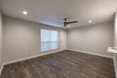 Located at 11800 Grant Rd in Cypress, TX, this single-floor residence offers a clean, contemporary design with a neutral color palette throughout. The open living area is anchored by warm wood-look flooring, recessed lighting, and a ceiling fan, creating a bright and airy atmosphere. Natural light flows in through a window with blinds near the front entry door, enhancing the welcoming feel of the space.

The kitchen is thoughtfully appointed with white shaker-style cabinetry, light quartz countertops, a classic white subway tile backsplash, a stainless steel sink, and a full-size stainless steel refrigerator. A peninsula with pendant lighting provides additional workspace and casual dining potential, seamlessly connecting the kitchen to the living area.

The bedroom features plush carpeting, a ceiling fan, and a window with blinds that invites natural light. A walk-in closet with dual wire shelving and hanging rods offers generous storage capacity and is finished with carpet flooring.

The bathroom is well-equipped with wood-look flooring, a toilet, and a tub-shower combination with dark tile surround and a decorative shower curtain. Clean white walls and practical fixtures complete the functional design. Overall, the space presents a well-maintained, move-in-ready environment suited for comfortable everyday living.