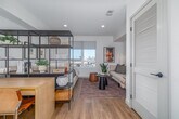 Located at 12888 Crenshaw Blvd in Hawthorne, California, this thoughtfully designed studio offers a smart, single-level layout that maximizes every square foot. Light wood-tone flooring flows throughout, tying together a cohesive and contemporary aesthetic against crisp white walls.

The galley-style kitchen is a standout feature, outfitted with gray shaker cabinetry extending to the ceiling, a textured mosaic tile backsplash, white quartz countertops, and a full suite of stainless steel appliances including a gas range, built-in microwave, dishwasher, and refrigerator. Matte black hardware and under-cabinet lighting add a refined finishing touch.

The open living area transitions seamlessly from the kitchen, offering space for both a sleeping area and a lounge. Large windows fill the room with natural light and frame views of the surrounding Hawthorne skyline. The combined layout is versatile, allowing for flexible furniture arrangements.

The bathroom is clean and well-appointed, featuring gray cabinetry with a backlit vanity mirror, consistent with the kitchen's design language, and durable wood-look flooring. A stacked in-unit laundry is conveniently integrated into the layout. Two closets provide ample storage, completing this well-organized and modern urban residence.