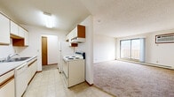 Located in Elk River, MN, this single-floor unit offers three bedrooms and one bathroom within a practical, well-organized layout. The galley-style kitchen is equipped with white cabinetry accented by wood trim, a double sink, a dishwasher, a coil-top electric range, and a refrigerator, all set over durable tile flooring. The kitchen opens toward the living area, which features carpeting and a sliding glass door that brings in natural light. A central hallway connects the bedrooms and bathroom, with warm wood-trimmed doors and neutral-toned walls throughout. The primary bedroom is generously sized, offering comfortable living space, carpet flooring, and baseboard heating. The two additional bedrooms are well-proportioned, each with carpet flooring, white walls, and baseboard heaters. One secondary bedroom features a window with natural light. The full bathroom includes a tub and shower combination, tile flooring, and a wood-trimmed vanity. Textured ceilings are consistent throughout the unit, adding a classic residential character. The overall aesthetic is clean and neutral, providing a functional and move-in ready living environment suitable for a variety of occupants.