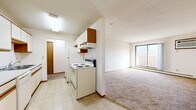 Located in Elk River, MN, this single-floor unit offers three bedrooms and one bathroom within a practical, well-organized layout. The galley-style kitchen is equipped with white cabinetry accented by wood trim, a double sink, a dishwasher, a coil-top electric range, and a refrigerator, all set over durable tile flooring. The kitchen opens toward the living area, which features carpeting and a sliding glass door that brings in natural light. A central hallway connects the bedrooms and bathroom, with warm wood-trimmed doors and neutral-toned walls throughout. The primary bedroom is generously sized, offering comfortable living space, carpet flooring, and baseboard heating. The two additional bedrooms are well-proportioned, each with carpet flooring, white walls, and baseboard heaters. One secondary bedroom features a window with natural light. The full bathroom includes a tub and shower combination, tile flooring, and a wood-trimmed vanity. Textured ceilings are consistent throughout the unit, adding a classic residential character. The overall aesthetic is clean and neutral, providing a functional and move-in ready living environment suitable for a variety of occupants.
