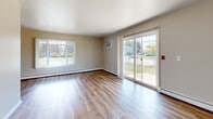 Located at 1356 Sunfield St in Sun Prairie, Wisconsin, this two-bedroom, one-bathroom single-floor residence offers a practical and comfortable layout across a well-proportioned floor plan. The living room is bright and open, featuring warm hardwood-style flooring, a large sliding glass door that frames outdoor views of the neighborhood, and an additional window fitted with vertical blinds that flood the space with natural light. Baseboard heating and a wall-mounted air conditioning unit ensure year-round comfort throughout the home. The galley-style kitchen is efficiently designed, lined on both sides with rich dark wood cabinetry, granite-toned countertops, and a full suite of appliances including a refrigerator, stove, and dishwasher. A ceiling fan overhead adds airflow to the space. Both bedrooms are carpeted for comfort and feature ceiling fans, window blinds for privacy, and sliding closet doors offering ample storage. The primary bedroom is generously sized with dual windows that bring in plenty of natural light. The full bathroom is well-appointed with a wood-toned vanity, white countertop, a combined tub and shower, and hardwood-style flooring. A connecting hallway ties all areas of the home together seamlessly.