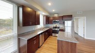 This single-floor residence features a thoughtfully designed open-concept layout that seamlessly connects the kitchen and living areas. The kitchen is a standout, equipped with rich dark-wood cabinetry, granite countertops, a central island for additional prep and seating space, and a full suite of stainless steel appliances including a gas range, dishwasher, microwave, and refrigerator. Recessed lighting and large windows fill the kitchen with natural light, offering pleasant outdoor views.

The living area extends from the kitchen, finished with light hardwood-style flooring and floor-to-ceiling windows that bring in generous natural light and views of the surrounding area. Bedrooms are carpeted for comfort and feature large windows and double-door closets providing ample storage. The neutral taupe tones used throughout create a cohesive, modern aesthetic.

Two full bathrooms include tub and shower combinations with chrome fixtures, light tile flooring, dark vanity cabinetry, and neutral wall tones. The overall ambiance of the space is clean, contemporary, and functional, with consistent finishes that lend a polished, move-in-ready feel throughout.