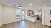 This contemporary three-story home in Dallas, TX offers a well-designed layout spread across three distinct levels. The entry level features a welcoming foyer with wood-look flooring, recessed lighting, and a staircase connecting the floors. The main living level showcases an open-concept design where the living room and kitchen flow seamlessly together. The kitchen is outfitted with stainless steel appliances—including a French door refrigerator, electric range, and built-in microwave—complemented by light wood cabinetry, a subway tile backsplash, white quartz countertops, and a peninsula with pendant lighting. A ceiling fan and access to natural light through multiple windows add to the airy feel of the living area. The three bedrooms are finished with plush carpet flooring, ceiling fans, and generous windows that bring in natural light. One bedroom features a built-in window seat with open shelving. The spacious primary bedroom includes a walk-in closet with multi-rod shelving. Both bathrooms are finished with large-format marble-style tile, including a soaking tub and shower combo. The home's cohesive use of light tones, wood-look flooring, and modern fixtures creates a clean, contemporary ambiance throughout.