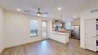 This contemporary three-story home in Dallas, TX offers a well-designed layout spread across three distinct levels. The entry level features a welcoming foyer with wood-look flooring, recessed lighting, and a staircase connecting the floors. The main living level showcases an open-concept design where the living room and kitchen flow seamlessly together. The kitchen is outfitted with stainless steel appliances—including a French door refrigerator, electric range, and built-in microwave—complemented by light wood cabinetry, a subway tile backsplash, white quartz countertops, and a peninsula with pendant lighting. A ceiling fan and access to natural light through multiple windows add to the airy feel of the living area. The three bedrooms are finished with plush carpet flooring, ceiling fans, and generous windows that bring in natural light. One bedroom features a built-in window seat with open shelving. The spacious primary bedroom includes a walk-in closet with multi-rod shelving. Both bathrooms are finished with large-format marble-style tile, including a soaking tub and shower combo. The home's cohesive use of light tones, wood-look flooring, and modern fixtures creates a clean, contemporary ambiance throughout.