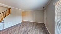 Located at 413 Amsterdam in Virginia Beach, Virginia, this two-story, two-bedroom, two-bathroom home offers a well-designed layout spread evenly across both floors. The main level features durable hardwood-style flooring throughout the living room and dining area, complemented by crown molding that adds a clean, finished look. The kitchen is equipped with white shaker-style cabinetry, light stone-look countertops, black appliances including a range, microwave, and dishwasher, and a window above the sink that brings in natural light. An adjacent laundry area conveniently houses a full-size washer and dryer. The upper level is home to both bedrooms, each finished with plush carpeting and ceiling fans with light fixtures. The generously sized primary bedroom offers a comfortable retreat with natural light from a large window. The second bedroom is equally well-appointed. The home includes two full bathrooms: one featuring a full tub-shower combination with clean white surround, and a second tucked under the roofline with warm wood-look flooring and a white vanity. With four closets and two hallways, storage and circulation are practical throughout. Neutral warm tones unify the home's interior, creating a calm and welcoming ambiance.