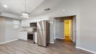 Located at 8014 Tommy Ct in Tampa, FL, this single-story home offers a clean, modern aesthetic highlighted by fresh neutral gray tones and durable wood-look vinyl flooring throughout. The open-concept living and kitchen area is anchored by dramatic vaulted ceilings that lend a sense of spaciousness and airiness to the main living space. The kitchen is well-appointed with crisp white shaker cabinets, granite-look countertops, a classic subway tile backsplash, and a full suite of stainless steel appliances including a refrigerator, electric range, and over-the-range microwave. A stylish pendant light fixture adds a decorative touch overhead. The living area flows seamlessly from the kitchen, benefiting from the same soaring ceilings and recessed lighting. Bedrooms are comfortably sized with neutral walls, vinyl flooring, and closet storage. The bathroom features a tub-shower combination, a white vanity, and coordinating flooring. A dedicated laundry area with in-unit washer and dryer hookups adds everyday convenience. The home's cohesive, updated interior design makes it a practical and attractive residence in the Tampa area.