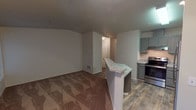Located at 1015 112th St E, Unit A308 in Tacoma, WA 98444, this single-floor residence offers a thoughtfully designed layout with modern finishes and functional living spaces. The open-concept living and kitchen area serves as the heart of the unit, where a peninsula with granite-style countertops creates a natural divide between the two spaces. The kitchen is well-equipped with stainless steel appliances, including a refrigerator, electric range, and dishwasher, complemented by gray shaker-style cabinetry and wood-look plank flooring. A ceiling fan in the living area adds both comfort and style, while plush carpeting creates a warm, inviting atmosphere. The bedroom is generously sized, featuring large windows that allow abundant natural light to fill the room and offer pleasant outdoor views. Soft carpeting and a baseboard heating unit complete the space. The bathroom features wood-look tile flooring and a full tub-shower combination, maintaining the clean, neutral aesthetic found throughout the unit. A utility area with additional storage and laundry access provides added convenience. Overall, the unit presents a clean, contemporary interior with a cohesive neutral palette, making it a comfortable and practical living space.