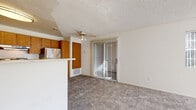 This single-story, one-bedroom, one-bathroom unit in Vallejo, California offers a efficiently arranged floor plan across a cozy footprint. The open-concept living area is carpeted and bathed in natural light from a wide bank of windows fitted with vertical blinds, providing views of the surrounding greenery. A ceiling fan is centrally positioned overhead, complementing the textured ceiling throughout the space.

The kitchen is separated from the living area by a peninsula counter with a textured finish, offering additional prep space and a casual divider between the two areas. Warm oak cabinetry lines the walls with abundant upper and lower storage, while stainless steel appliances — including a refrigerator and electric range — are paired with a double basin sink and light countertops. Tile flooring distinguishes the kitchen from the carpeted areas.

The bedroom is a well-proportioned room with multiple windows that allow generous natural light to fill the space. A sliding mirrored closet door opens to a reach-in closet with built-in shelving, providing organized storage. The full bathroom features a tub and shower combination with a sliding glass enclosure, a wood-framed vanity with granite-style countertop, and tile flooring.