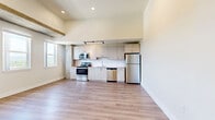 Located at 5800 W Alameda Ave in Lakewood, Colorado, this two-bedroom, one-bathroom residence offers a well-designed single-level layout finished with light hardwood flooring that flows consistently throughout every room. The open living and kitchen area makes an immediate impression with its soaring ceilings and striking exposed wood beam accents, creating an industrial-modern aesthetic that sets the tone for the entire unit. The kitchen is equipped with a full suite of stainless steel appliances—including a range, microwave, dishwasher, and refrigerator—complemented by light wood cabinetry, a clean white backsplash, and track lighting overhead. Both bedrooms are bright and comfortable, featuring the same hardwood flooring, crisp white walls, and exposed beam details. The secondary bedroom benefits from dual windows that invite generous natural light and offer views of the surrounding Lakewood neighborhood. The primary bedroom provides access to a hallway leading to the shared bathroom and closet space. The bathroom is finished with a light wood vanity, a large framed mirror, and hardwood-style flooring, maintaining the cohesive modern aesthetic found throughout the unit. Clean panel doors and neutral tones complete the polished, move-in-ready feel of this Lakewood residence.