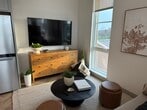 This 580 square foot apartment in Elkhart, Indiana, exemplifies modern urban living with its thoughtful design and efficient use of space. The open floor plan seamlessly integrates the kitchen, living area, and bedroom, creating a spacious feel despite its compact size.

The kitchen is a standout feature, boasting white cabinetry, stainless steel appliances, and a large central island with a marble countertop. A stylish lantern-style pendant light adds character, while the adjacent mobile cart offers additional functionality.

The bathroom is a study in contemporary design, featuring a glass-enclosed shower, grey vanity, and decorative wall accents. Herringbone pattern wood flooring runs throughout the apartment, adding warmth and visual interest.

Large windows flood the space with natural light and offer stunning views of the surrounding area. The living area is comfortably furnished with a plush sofa and a unique room divider that doubles as a headboard for the bedroom space.

Clever storage solutions, including built-in cabinets and a wooden dresser, maximize the available space. The overall aesthetic is clean and uncluttered, with neutral tones accented by carefully chosen decor elements. This apartment successfully balances style and functionality, creating an inviting home in a compact urban setting.