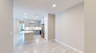 This single-floor residence offers a thoughtfully designed layout encompassing three bedrooms and three full bathrooms. The open-concept living and kitchen area serves as the heart of the home, where light wood-look flooring, recessed lighting, and a neutral warm-beige color palette create a clean, contemporary ambiance. A ceiling fan in the living room enhances comfort, while a door provides direct access to an outdoor balcony area, bringing in natural light.

The kitchen is well-equipped with gray shaker-style cabinetry, white quartz countertops, a subway tile backsplash, a built-in kitchen island with outlets, and a full suite of stainless steel appliances including a refrigerator, range, and built-in microwave. Open shelving adds a modern touch.

The bedrooms feature plush carpeting and ceiling fans, with windows allowing natural light to filter through. The primary bedroom connects directly to an en-suite bathroom with warm cabinetry and vanity lighting. The bathrooms are finished with marble-style tile surrounds in the walk-in glass-enclosed showers, light tile flooring, and chrome fixtures, maintaining a consistent, polished aesthetic throughout the home.