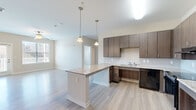 Located at 1140 Bridgefield Pl in Charlotte, NC, this single-floor, 4-bedroom, 3-bathroom home offers a well-designed layout built for both comfort and practicality. The entrance opens into a hallway with built-in storage, leading seamlessly toward the main living areas. The open-concept kitchen is a standout feature, showcasing dark walnut-toned cabinetry, granite countertops, a subway tile backsplash, and a central island with pendant lighting overhead — all complemented by black appliances including a gas range and refrigerator. The kitchen flows naturally into the living room, which is bright and airy thanks to large windows and a glass door that opens to an outdoor deck, inviting natural light throughout. Light wood-tone laminate flooring runs through the main living areas, while the bedrooms feature plush carpeting and ceiling fans. Each bedroom includes closet space with built-in wire shelving. The three bathrooms are thoughtfully equipped with accessibility features, including grab bars and a tub bench, reflecting a design mindful of diverse needs. Clean neutral tones and recessed lighting throughout give the home a fresh, modern feel well-suited for everyday living.