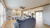 This single-story home offers a thoughtfully designed layout across three bedrooms and two bathrooms, blending modern finishes with a warm, inviting aesthetic. The open-concept living and kitchen area serves as the heart of the home, featuring light wood-look flooring, exposed beam accents, and a ceiling fan overhead. The living room provides generous seating space with easy sightlines to the kitchen, which is highlighted by white shaker-style cabinetry, quartz countertops, a farmhouse sink, stainless steel appliances, and a central island with pendant lighting — ideal for both cooking and casual dining. A sliding door off the kitchen leads to an outdoor deck, allowing natural light to flow freely into the space. The bedrooms are carpeted for comfort, each with windows that bring in natural light. The primary bedroom includes a dedicated walk-in closet fitted with wire shelving for organized storage. The bathrooms are clean and functional, with one featuring a full tub and shower combination with oil-rubbed bronze fixtures. A dedicated entrance and closet round out the floor plan, adding convenience and practicality to this well-organized single-floor home.