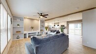 This single-story home offers a thoughtfully designed layout across three bedrooms and two bathrooms, blending modern finishes with a warm, inviting aesthetic. The open-concept living and kitchen area serves as the heart of the home, featuring light wood-look flooring, exposed beam accents, and a ceiling fan overhead. The living room provides generous seating space with easy sightlines to the kitchen, which is highlighted by white shaker-style cabinetry, quartz countertops, a farmhouse sink, stainless steel appliances, and a central island with pendant lighting — ideal for both cooking and casual dining. A sliding door off the kitchen leads to an outdoor deck, allowing natural light to flow freely into the space. The bedrooms are carpeted for comfort, each with windows that bring in natural light. The primary bedroom includes a dedicated walk-in closet fitted with wire shelving for organized storage. The bathrooms are clean and functional, with one featuring a full tub and shower combination with oil-rubbed bronze fixtures. A dedicated entrance and closet round out the floor plan, adding convenience and practicality to this well-organized single-floor home.