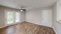 Located at 805 Indian Trail Dr in Kingsport, Tennessee, this single-floor unit offers a clean, modern layout designed for comfortable everyday living. Wood-look plank flooring runs consistently throughout the space, lending a cohesive and low-maintenance aesthetic to every room. The main living area is bright and open, highlighted by a ceiling fan with light kit and French doors that invite natural light and provide direct access to the outdoors. A dedicated entry door offers a clear separation between the living space and the outside. The kitchen is functionally equipped with warm wood cabinetry, light countertops, and black appliances including a refrigerator, range, and dishwasher, all arranged in an efficient galley-style layout. The bedrooms are comfortably sized, each featuring ceiling fans, natural light from windows with blinds, and access to closet space. The bathrooms include wood-look flooring, vanities with storage, and tub-shower combinations. A dedicated laundry area houses a full-size washer and dryer alongside overhead shelving for additional storage. Neutral gray walls throughout the unit provide a versatile backdrop, while clean white trim and doors add a crisp, finished look to the overall interior.