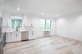 This single-floor space showcases a clean, contemporary design highlighted by light-toned hardwood flooring that runs seamlessly throughout. The open layout connects the kitchen and living areas, creating a bright and airy atmosphere enhanced by recessed lighting and multiple windows framing views of surrounding greenery.

The kitchen is thoughtfully outfitted with crisp white shaker cabinets, light stone countertops, a matte black faucet, subway tile backsplash, and a stainless steel dishwasher. Natural light pours in through multiple windows, reinforcing the fresh, modern aesthetic.

The bedrooms are generously sized with large windows offering outdoor views, wall-unit HVAC systems, and ample closet space with dedicated storage areas accessible via white panel doors with matte black hardware.

Two bathrooms serve the unit. One features bold blue walls, a white vanity with marble-style countertop, and a backlit mirror. The second includes a soaking tub and shower combination fully clad in classic white subway tile with matte black fixtures, delivering a sharp, contemporary contrast.

Throughout, consistent use of white walls, light wood flooring, and matte black accents creates a cohesive, modern aesthetic.
