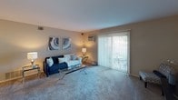 This single-story residence in Carol Stream, Illinois, presents a thoughtfully arranged floor plan that balances functionality and comfort. The living room features neutral-toned walls, plush carpeting, and a sliding glass door dressed with vertical blinds that allows natural light to filter in while providing access to an outdoor area. A wall-mounted television setup and a dedicated media console make the space well-suited for everyday living.

Adjacent to the living area, the dining space accommodates a full-sized table and chairs beneath a pendant light fixture, with a convenient storage closet nearby. The galley-style kitchen is equipped with stainless steel appliances, including a gas range, microwave, and refrigerator, complemented by rich dark cabinetry, light countertops, and wood-look flooring that adds warmth throughout.

The bedroom is generously proportioned, featuring soft carpeting, a ceiling fan, a large closet, and a window that brings in natural light. Two bathrooms serve the unit: one features a tub-shower combination with tiled surround and wood-look flooring, while the other offers a vanity with a light countertop, dark cabinetry, and a well-lit mirror. Neutral tones throughout create a cohesive, move-in-ready ambiance.