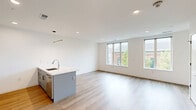 Located at 801 N Orange Street in Wilmington, Delaware, this modern 2-bedroom, 2-bathroom unit offers a thoughtfully designed layout with clean lines and contemporary finishes throughout. Light wood-tone flooring flows seamlessly across the entire space, complementing the crisp white walls and creating a bright, cohesive aesthetic.

The open-concept kitchen and living area serves as the heart of the unit. The kitchen is equipped with stainless steel appliances, including a refrigerator, range, and microwave, paired with sleek grey cabinetry featuring matte black hardware. A large island with a white quartz countertop and undermount sink anchors the space and provides additional seating and prep areas. Pendant lighting above the island adds a modern accent.

Both bedrooms are well-proportioned, with the primary bedroom offering generous space and large windows that flood the room with natural light and provide views of the surrounding neighborhood. The second bedroom also benefits from natural light through its own window.

The two bathrooms share a consistent modern design, each featuring large-format tile flooring, a wall-mounted vanity light, a framed mirror, and a natural wood-toned vanity with a white countertop and undermount sink. One bathroom includes a tub-shower combination with marble-style tile surround, while the other features a standing shower. A closet provides dedicated storage to complete this well-appointed unit.