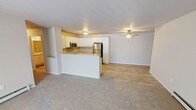 Located at 1615 Webster Way in Waupaca, Wisconsin, this single-floor unit offers a well-designed, open-concept layout that seamlessly connects the kitchen and living areas. The kitchen is equipped with stainless steel appliances, including a refrigerator, range, and over-the-range microwave, complemented by crisp white cabinetry and granite-style countertops. A peninsula with a matching countertop provides additional workspace and serves as a natural divider between the kitchen and the carpeted living area, which features a ceiling fan and baseboard heating. A hallway leads to the bedrooms, each finished with plush carpet, baseboard heating, and closets with wire shelving. Natural light enters through the bedroom windows, adding brightness to the neutral color palette throughout. The bathrooms are appointed with granite-style vanity tops, white cabinetry, wood-look tile flooring, and walk-in showers with grab bars. A dedicated laundry room with wire shelving, wood-look flooring, and an in-unit washer and dryer adds everyday convenience. The consistent use of light tones, wood-look flooring in key areas, and clean finishes gives the entire space a fresh, functional character suited for comfortable living.