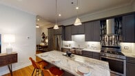 Located in Chicago's vibrant West Loop neighborhood, this single-floor residence at 1038 W Monroe St offers a thoughtfully designed layout with modern finishes throughout. The chef's kitchen serves as the heart of the home, showcasing charcoal gray shaker cabinets with under-cabinet lighting, striking marble-look countertops, a stainless steel farmhouse sink, and a full suite of stainless steel appliances including a gas range and dishwasher. A mosaic tile backsplash adds visual interest near the range, while a large island with seating provides an ideal space for casual dining and entertaining. Crown molding throughout the unit adds an architectural detail that elevates the overall aesthetic. The living area features warm hardwood floors, soft neutral walls, and recessed lighting, creating a welcoming and versatile space. Two well-proportioned bedrooms offer comfortable retreats, each featuring hardwood flooring, crown molding, and ample natural light. The full bathroom is finished with large-format neutral tiles, a marble-top vanity with white cabinetry, and a tub-shower combination. The cohesive design palette of warm neutrals, charcoal, and wood tones creates a refined yet inviting atmosphere throughout the entire residence.