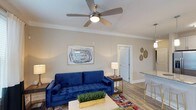Located at 6701 Fox Rd in Raleigh, North Carolina, this single-floor home offers a well-designed layout with a warm and inviting atmosphere. The living area serves as the heart of the space, featuring smooth, neutral-toned walls, crown molding, and durable wood-style flooring that adds a clean, contemporary feel. A ceiling fan with a built-in light fixture centers the room, providing both comfort and functionality. The open layout allows for a natural flow between the living and kitchen areas, with the kitchen visible just off the main room and highlighted by a countertop bar area — ideal for casual dining or entertaining. Large doorways connect the rooms seamlessly, contributing to an airy, open feel throughout the home. The overall design balances practicality with style, offering a move-in-ready environment that suits a variety of living arrangements. Neutral wall tones and natural light work together to create a bright and comfortable interior that feels welcoming from every angle. This single-story property in Raleigh combines functional design with accessible, everyday livability.