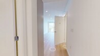 Located at 5670 Cambie St in Vancouver, BC, this efficiently designed one-bedroom, one-bathroom unit offers a clean, contemporary aesthetic throughout. Light-toned hardwood flooring runs continuously across the open layout, complementing the crisp white walls and recessed lighting that keep the space feeling bright and airy.

The kitchen is thoughtfully appointed with flat-panel cabinetry in a soft grey-white finish, a glass tile backsplash, stainless steel appliances including a full-size refrigerator and electric range, and a sleek countertop with an undermount sink. A stacked washer and dryer unit is conveniently integrated into the hallway area, adding practical in-unit laundry without sacrificing flow.

The bedroom is a calm, minimalist retreat featuring large floor-to-ceiling sliding glass doors that open to a balcony, filling the room with natural light and offering open views of the surrounding Vancouver cityscape and greenery. The hallways connect each room efficiently, maintaining a logical and uncluttered layout.

The bathroom is finished with neutral stone-toned floor tiles, a vessel sink set on a modern vanity with drawer storage, a framed mirror, and a full-size soaker tub with a tiled surround. The overall design of the unit reflects a modern, urban sensibility with quality finishes throughout.