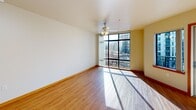 Located in Portland's vibrant Pearl District, this two-bedroom, one-bathroom residence offers a well-organized single-floor layout designed for comfortable urban living. The living and dining area is bright and open, anchored by large floor-to-ceiling windows that flood the space with natural light and frame expansive city views. Wood-style flooring runs throughout the main living areas, adding warmth and continuity, while a ceiling fan provides year-round comfort. A balcony accessible from the main living area extends the living space outdoors. The galley-style kitchen is efficiently laid out with light wood cabinetry, ample counter space, and a full suite of white appliances including a range, refrigerator, dishwasher, and over-the-range microwave. A secondary wet bar area with upper cabinetry and a sink provides additional utility. Both bedrooms feature neutral carpet, vertical blinds, ceiling fans, and baseboard heating, creating a quiet and comfortable retreat. Three closets throughout the unit offer generous storage. The bathroom is clean and functional, featuring a tub/shower combination with a grab bar. A dedicated entrance and hallway provide a practical transition into the home, completing this well-appointed urban residence.