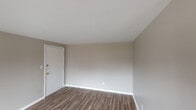 This single-floor unit offers a straightforward, well-maintained layout designed for comfortable everyday living. The living area is open and bright, finished with warm wood-look laminate flooring and neutral greige walls that create a clean, versatile backdrop. A wall-mounted mini-split unit provides climate control, and a private entry door leads directly into the space.

The kitchen is efficiently arranged with ample white upper and lower cabinetry, dark countertops, a tiled backsplash, and a double-basin sink. White appliances — including a refrigerator, electric range with coil burners, and an integrated range hood — are all included. The kitchen connects seamlessly to the living area, reinforcing the open flow of the floor plan.

The bedroom is a well-proportioned room featuring the same wood-look flooring, neutral walls, white trim, and a window that allows natural light to filter in, offering a view of the surrounding exterior.

The bathroom is fully equipped with a single-sink vanity topped with a wood-toned cabinet, a wall mirror with sconce lighting, a toilet, and a full soaking tub with a tiled surround. A window above the tub brings in additional natural light. Throughout the unit, consistent flooring, neutral tones, and clean finishes give the space a cohesive, move-in ready character.
