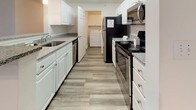 This single-floor residence offers a thoughtfully designed layout with a clean, neutral aesthetic throughout. The living area is a welcoming focal point, anchored by a fireplace and ceiling fan, with wood-look plank flooring that extends through the main living spaces. Natural light filters in through a sliding glass door, adding brightness and an airy feel to the room.

The kitchen is well-equipped with white cabinetry, granite-look countertops, and a full suite of stainless steel appliances, including an electric range, refrigerator, microwave, and dishwasher. A convenient in-unit laundry area is accessible directly from the kitchen, adding a practical and desirable amenity. The kitchen connects seamlessly to the main living and dining areas.

The bedrooms are carpeted for comfort and each feature ceiling fans with light fixtures. Closet storage is provided, with built-in shelving and hanging rods visible in at least one bedroom. The bathrooms are finished with wood-look tile flooring, white vanities with under-sink storage, and full tub-shower combinations. A welcoming entry hallway with a paneled front door completes the layout, offering a smooth transition into the main living spaces.