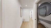 Located in the heart of Beverly Hills, this thoughtfully designed 2-bedroom, 5-bathroom residence offers a seamless blend of modern luxury and warm, natural materials throughout. Light hardwood flooring flows across the entire single-level layout, unifying each space with an airy, cohesive aesthetic.

The open living room features crisp white walls, recessed lighting, and black-framed windows that invite abundant natural light, complemented by a curated neutral palette. The foyer makes a welcoming first impression with clean architectural lines and gallery-worthy wall space.

The chef's kitchen is outfitted with flat-front light oak cabinetry, a dramatic marble-slab backsplash, stone countertops, a built-in induction cooktop, stainless steel double ovens, and a stainless range hood — all illuminated by a large window overlooking greenery outside.

The primary bedroom is generously proportioned, featuring floor-to-ceiling sliding glass doors that open to a private balcony with outdoor views. Its en-suite bath impresses with a wide double-sink vanity, illuminated LED mirror, light oak cabinetry, and a spacious glass-enclosed walk-in shower with a built-in bench. A second stylish bathroom features a floating vanity with a backlit round mirror and elegant pendant lighting. Both bedrooms are bright, serene, and well-appointed with dedicated closet space.