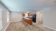 This single-story residence on Flint Hill Lane in Bessemer, Alabama, offers a practical and functional layout designed for comfortable everyday living. The open-concept kitchen and living area serves as the heart of the home, where wood-look vinyl flooring transitions seamlessly into carpeted living space. The kitchen is equipped with warm-toned medium wood cabinetry, a peninsula with counter seating, a double sink, black appliances including a range and full-size refrigerator, and ample upper and lower cabinet storage. Recessed and flush-mount lighting illuminates the space throughout.

The bedrooms are carpeted and finished in neutral tones, each featuring a ceiling fan with light fixture and window with blinds that allow natural light to filter in. Closet access is provided in the bedroom areas, as visible in the floor plan. The bathroom includes a full-size soaking tub and shower combination with white tile surround, chrome fixtures, and a clean, straightforward design. Neutral gray walls and white trim are consistent throughout the unit, creating a cohesive and understated aesthetic well-suited for a variety of furnishing styles.