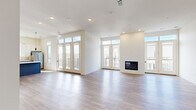 Located in Leawood, Kansas, this thoughtfully designed single-floor residence offers four bedrooms and four bathrooms within a generous, well-appointed layout. The open-concept living room is a standout centerpiece, featuring a sleek built-in fireplace, light hardwood-style flooring, recessed lighting, and a wall of French doors flanked by transom windows that flood the space with natural light and provide access to an outdoor balcony. The modern kitchen is outfitted with two-tone cabinetry — slate-blue lower cabinets paired with crisp white uppers — complemented by a tile backsplash, white quartz countertops, stainless steel appliances, and a kitchen island. Each of the four bedrooms is carpeted and features large windows with outdoor views, including treetop and balcony vistas. The primary bedroom connects directly to a private en-suite bathroom. The bathrooms throughout are consistently finished with floating gray vanities, white quartz countertops, large mirrors, and wood-look tile flooring, with at least one featuring a walk-in shower. Closet spaces include walk-in configurations with wire shelving. A dedicated laundry area houses a stacked washer and dryer unit. The overall aesthetic is clean, contemporary, and move-in ready.