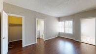 Located at 520 S Mariposa Ave in the Koreatown neighborhood of Los Angeles, this single-floor unit offers a straightforward and functional layout with consistent finishes throughout. The living and bedroom areas feature rich, dark hardwood flooring that contrasts cleanly against neutral, light gray textured walls and white trim. Windows fitted with horizontal blinds allow natural light to filter into the rooms, creating a bright and open atmosphere. The bedroom includes direct access to a closet and an en-suite bathroom, providing a practical and private layout. The bathroom is finished with light ceramic tile flooring, white wall tiling, a single-vanity with cabinet storage, a full soaking tub with shower, and a window that brings in additional natural light. The kitchen runs in a galley-style configuration, featuring light tile flooring, white cabinetry, and space for full-sized appliances including a refrigerator and range. Ceilings throughout feature a textured finish, adding subtle architectural character to the otherwise clean and neutral interior palette. The overall ambiance is calm and utilitarian, offering a solid foundation well-suited for personalization in a central Los Angeles location.