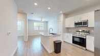 This well-appointed one-bedroom, one-bathroom unit offers a thoughtfully designed open-concept layout that maximizes its comfortable footprint. Light wood-look flooring runs throughout the entire space, lending a clean and cohesive aesthetic from room to room.

The kitchen is a standout feature, equipped with crisp white shaker cabinetry, granite countertops, and a full suite of stainless steel appliances including a range, over-the-range microwave, and a side-by-side refrigerator. A central kitchen island with a built-in sink and additional granite surface space provides both functionality and a natural gathering point. The kitchen flows seamlessly into the living room, which benefits from natural light through a window and is topped with a ceiling fan for added comfort.

The bedroom is a well-proportioned retreat, featuring a ceiling fan, a window with blinds offering natural light, and direct access to a dedicated walk-in closet outfitted with wire shelving for organized storage.

The bathroom is elegantly finished with a granite-topped vanity, white cabinetry, a wide mirror with overhead lighting, and a soaking tub framed by marble-style tile surround. Consistent light wood flooring ties the bathroom seamlessly to the rest of the unit.

Overall, the space presents a bright, modern, and move-in-ready environment with quality finishes throughout.
