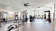 Located in Wildwood, FL, this fitness center offers a thoughtfully designed exercise space that supports a wide range of workout routines. The single-floor layout provides a generous, open floor plan with soaring vaulted ceilings that create an airy, expansive atmosphere. Large windows along multiple walls flood the interior with natural light and offer views of the surrounding outdoor environment, enhancing the overall workout experience.

The space is outfitted with an impressive selection of equipment catering to both strength and cardio training. Strength equipment includes multi-station cable machines, a power rack with bench press, a full dumbbell rack with flat and adjustable benches, and a dedicated free weights area. A large wall mirror runs alongside the free weights section, allowing for proper form checks during training. The cardio zone features treadmills, a stationary bike, and an air bike, while a functional training station stocks kettlebells, medicine balls, a punching bag, and a TKO functional rig. A wall-mounted television provides entertainment during workouts.

Durable flooring throughout and multiple large ceiling fans ensure comfort during intense sessions. Direct outdoor access via glass-panel doors adds convenience. The clean, white and neutral color palette, accented by an inspirational "Keep Growing" wall graphic, creates a motivating and professional environment.