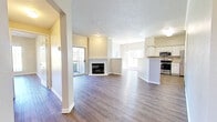 Located in Littleton, Colorado, this single-floor residence offers a well-designed open-concept layout that promotes a sense of spaciousness throughout. The main living area is anchored by a corner fireplace with a white-trimmed surround, complemented by crown molding, a textured ceiling, and wood-style flooring that flows seamlessly across the space. Large sliding glass doors and multiple windows invite abundant natural light and provide views of the surrounding outdoor landscape.

The kitchen is appointed with white cabinetry, light countertops, and a full suite of stainless steel appliances including a range, over-the-range microwave, and refrigerator. A raised peninsula counter separates the kitchen from the living and dining areas, creating a practical and open flow. The layout also reveals a built-in shelving niche, offering additional storage and display options.

The bedroom is a comfortable, well-lit room featuring a ceiling fan, a large window, and the same wood-style flooring found throughout the unit. The bathroom includes a white vanity with a broad countertop, a large mirror, and coordinating cabinetry, maintaining the clean, neutral aesthetic consistent across the entire space.