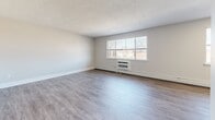 Located at 464 Spencerport Rd in Rochester, NY, this one-bedroom, one-bathroom unit offers a well-organized single-floor layout designed for comfortable everyday living. The spacious living area features light gray luxury vinyl plank flooring, a textured ceiling, baseboard heating, and a wall-unit air conditioner. A large multi-pane window allows natural light to fill the room, providing views of the surrounding neighborhood. The kitchen is efficiently designed with white shaker-style cabinetry, light countertops, a stainless steel sink, dishwasher, range, and a built-in microwave, complemented by matching LVP flooring and a window above the sink. The bedroom is generously sized, finished with plush carpeting, and features two windows that bring in additional natural light along with a wall-unit AC and baseboard heater. A full-width bifold closet provides ample storage. The bathroom is clean and contemporary, with white shaker vanity cabinetry, brushed nickel hardware, and LVP flooring. A hallway connects all areas of the unit, providing a logical and functional flow throughout. The overall aesthetic is neutral and modern, with light tones and updated finishes throughout.