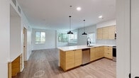 Located at 4041 Radford Ave in Studio City, California, this single-floor residence showcases a clean, contemporary design with a cohesive aesthetic carried throughout every room. The heart of the home is an open-concept kitchen and living area, where light wood cabinetry, white quartz countertops, and a geometric tile backsplash create a modern, inviting atmosphere. A generous kitchen island with a built-in sink serves as a functional centerpiece, illuminated by a pair of striking black pendant lights. Stainless steel appliances, including a refrigerator, range, and over-the-range microwave, complete the well-appointed kitchen. Light wood-tone flooring flows seamlessly across the entire space, unifying each area with warmth and continuity. The living area is bathed in natural light from multiple windows fitted with horizontal blinds, offering views of lush greenery outside. The bedroom continues the bright, airy feel with its own window, a ceiling fan for added comfort, and the same warm flooring. The bathroom features a wood-fronted vanity with a white countertop, a round mirror with a black frame, matte black fixtures, and a full shower-tub combo, delivering a stylish yet functional design. The overall ambiance is fresh, modern, and move-in ready.