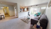 This thoughtfully designed new construction residence offers two bedrooms and one and a half bathrooms across a single, efficiently laid-out floor. The open-concept living area is anchored by plush carpeting and flows seamlessly toward a wall of sliding glass doors, filling the space with abundant natural light and providing views of the surrounding greenery. A dedicated dining nook with hardwood-style flooring and overhead lighting sits adjacent to the kitchen, offering a casual spot for everyday meals.

The kitchen is well-appointed with dark walnut-toned cabinetry, light stone-finish countertops, and stainless steel appliances including a dishwasher, range, and built-in microwave. A peninsula with bar seating connects the kitchen to the living area, enhancing the open feel. Multiple windows allow natural light to pour in from multiple angles.

Both bedrooms are carpeted and comfortably sized, each with windows overlooking the outdoors. The full bathroom features a tub-shower combination with clean white tile, while the half bath includes a vanity with matching cabinetry and tile flooring. Clean lines, neutral tones, and recessed lighting throughout contribute to a bright, modern ambiance.