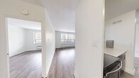 Located on the 4th floor at 7 Elizabeth St N in Mississauga, this well-appointed one-bedroom, one-bathroom unit offers a clean, modern interior with a thoughtful layout across a comfortable floor plan. Light wood-tone laminate flooring runs throughout the living areas and bedroom, creating a bright and cohesive aesthetic against crisp white walls.

The open-concept living and dining area is generously sized, featuring large windows that flood the space with natural light and provide views of the surrounding Mississauga cityscape. A baseboard heating unit sits beneath the windows, ensuring year-round comfort. The space flows seamlessly from the entrance hallway into the main living area.

The kitchen is efficiently designed with rich dark cabinetry, stainless steel appliances including a full-size refrigerator, and tile flooring that contrasts nicely with the rest of the unit.

The bedroom offers a tranquil retreat with its own large window overlooking the city, light hardwood flooring, and a sliding-door closet providing ample storage. A second closet is also available within the unit.

The bathroom features a full soaking tub surrounded by elegant horizontal taupe tile with a white accent stripe, lending a clean and contemporary feel.

A private balcony extends the living space outdoors, offering open views of the Mississauga skyline and surrounding streetscape.