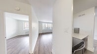 Located on the 4th floor at 7 Elizabeth St N in Mississauga, this well-appointed one-bedroom, one-bathroom unit offers a clean, modern interior with a thoughtful layout across a comfortable floor plan. Light wood-tone laminate flooring runs throughout the living areas and bedroom, creating a bright and cohesive aesthetic against crisp white walls.

The open-concept living and dining area is generously sized, featuring large windows that flood the space with natural light and provide views of the surrounding Mississauga cityscape. A baseboard heating unit sits beneath the windows, ensuring year-round comfort. The space flows seamlessly from the entrance hallway into the main living area.

The kitchen is efficiently designed with rich dark cabinetry, stainless steel appliances including a full-size refrigerator, and tile flooring that contrasts nicely with the rest of the unit.

The bedroom offers a tranquil retreat with its own large window overlooking the city, light hardwood flooring, and a sliding-door closet providing ample storage. A second closet is also available within the unit.

The bathroom features a full soaking tub surrounded by elegant horizontal taupe tile with a white accent stripe, lending a clean and contemporary feel.

A private balcony extends the living space outdoors, offering open views of the Mississauga skyline and surrounding streetscape.