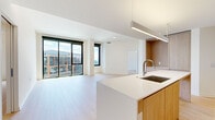 Located in Washington, DC's vibrant Union Market neighborhood, this modern residence offers four bedrooms and three bathrooms across a thoughtfully designed single-floor layout. The open-concept kitchen and living area serves as the heart of the home, anchored by a large center island with a white quartz countertop, an undermount sink, and a gas cooktop. Warm wood cabinetry lines the kitchen walls, complemented by sleek pendant lighting and light hardwood flooring that extends throughout the living spaces. Floor-to-ceiling sliding glass doors flood the living room with natural light and frame expansive views of the Washington, DC skyline and surrounding urban landscape. The bedrooms are bright and airy, with large windows — including one room with direct access to a wall of glass overlooking the city. The primary bedroom is generously sized and features a well-organized walk-in closet with built-in shelving and hanging rods. Two closets total provide ample storage throughout the unit. The three bathrooms are finished in a clean, contemporary style with large-format tile flooring, floating white vanities, oversized mirrors, and glass-enclosed walk-in showers. The overall aesthetic is modern and minimalist, offering a refined urban living experience.