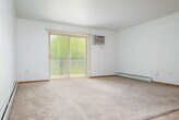 Located at 515 S 68th Ave in Wausau, Wisconsin, this well-organized single-floor home offers two bedrooms, two bathrooms, and a comfortable, practical layout across a generous footprint. The living area is bright and open, featuring light-toned carpet, light wood-style flooring at the entry, a ceiling fan, baseboard heating, and a wall-mounted air conditioning unit. A large sliding glass door with vertical blinds fills the space with natural light and provides outdoor access. The kitchen is equipped with warm oak cabinetry, white appliances including a range, over-the-range microwave, and refrigerator, complemented by light wood-style flooring and ample counter space in a U-shaped layout. The primary bedroom is well-sized, with carpet flooring, a ceiling fan, and a window offering natural light. Both bathrooms feature light wood-style vinyl flooring and warm oak vanities; one includes a full tub-shower combination. Two closets provide dedicated storage throughout the home. The hallway connects the bedrooms and bathrooms efficiently. The attached garage is spacious with a concrete floor, automatic opener, and an interior access door, offering secure parking and additional storage potential.