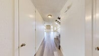 Located at 1000 Dumont Blvd in Las Vegas, NV, this two-bedroom, two-bathroom two-story home offers a well-planned layout spread across two floors. The main level features a bright and open living room highlighted by a striking natural stone accent wall and sliding glass doors that lead to a private patio, flooding the space with natural light. Light wood-style flooring runs throughout the lower level, complementing the clean, neutral palette. The kitchen is outfitted with white cabinetry, light stone countertops, a double-basin sink, and a window overlooking the exterior. A staircase with carpet treads and white railings connects the two floors. The upper level hosts both bedrooms, each with plush carpet flooring. The generously sized primary bedroom includes a walk-in closet with built-in shelving, offering ample storage. The second bedroom features a built-in closet as well. Both bathrooms are finished with wood-style flooring, white cabinetry, stone-topped vanities, large mirrors, and windows for natural light. One bathroom includes a full soaking tub and shower combination. The textured ceilings and consistent bright, white finishes throughout give the home a clean and functional character.