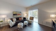 This single-floor residence is thoughtfully designed to offer a comfortable and functional living experience. The living area serves as the heart of the home, featuring rich dark hardwood flooring, neutral walls, and a large sliding glass door fitted with vertical blinds that opens to an outdoor balcony, allowing natural light and views of surrounding greenery to fill the space.

The kitchen is a standout feature, equipped with dark espresso cabinetry that extends to the ceiling for ample storage, light granite countertops, and a full suite of stainless steel appliances including a refrigerator, gas range, built-in microwave, and dishwasher. Light wood-tone flooring and recessed track lighting complete the kitchen's clean, contemporary look.

The bedroom is a serene retreat with plush wall-to-wall carpeting, soft neutral tones, and dual windows that invite natural light. A walk-in closet is accessible from the bedroom, providing generous storage. The bathroom is finished with dark cabinetry, granite countertops, a single undermount sink, and durable wood-look flooring, offering a polished and practical space. Throughout, the residence maintains a cohesive, modern aesthetic with quality finishes and a warm, inviting ambiance.
