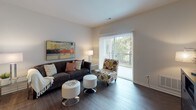 This single-floor residence is thoughtfully designed to offer a comfortable and functional living experience. The living area serves as the heart of the home, featuring rich dark hardwood flooring, neutral walls, and a large sliding glass door fitted with vertical blinds that opens to an outdoor balcony, allowing natural light and views of surrounding greenery to fill the space.

The kitchen is a standout feature, equipped with dark espresso cabinetry that extends to the ceiling for ample storage, light granite countertops, and a full suite of stainless steel appliances including a refrigerator, gas range, built-in microwave, and dishwasher. Light wood-tone flooring and recessed track lighting complete the kitchen's clean, contemporary look.

The bedroom is a serene retreat with plush wall-to-wall carpeting, soft neutral tones, and dual windows that invite natural light. A walk-in closet is accessible from the bedroom, providing generous storage. The bathroom is finished with dark cabinetry, granite countertops, a single undermount sink, and durable wood-look flooring, offering a polished and practical space. Throughout, the residence maintains a cohesive, modern aesthetic with quality finishes and a warm, inviting ambiance.