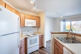 Located at 9222 Waterside St in Madison, WI, this one-bedroom, one-bathroom residence offers a well-designed single-floor layout that maximizes functionality and comfort. The combined kitchen and living area serves as the heart of the home, featuring rich hardwood-style flooring that flows throughout the main space. The kitchen is equipped with warm honey-toned cabinetry, white appliances including a refrigerator, electric range, and built-in microwave, along with a peninsula with a built-in sink — ideal for meal prep and casual dining. Track lighting overhead adds a bright, functional touch. The living area is anchored by a classic fireplace with a wood-trimmed surround, adding warmth and character to the space. Large windows flood the room with natural light and offer pleasant outdoor views of the surrounding greenery. The bedroom is a comfortable retreat featuring plush carpeting, a ceiling fan with light fixture, a generously sized closet, and a window that brings in additional natural light. The bathroom features a clean, full-sized tub and shower combination with white surround walls. Baseboard heating throughout ensures year-round comfort. This residence offers a cohesive, practical layout suited for easy everyday living.