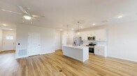Located at 7231 Weymouth in Perrysburg, Ohio, this well-designed single-floor home offers two bedrooms and two bathrooms with a thoughtful, modern layout. The open-concept kitchen and living area serves as the heart of the home, featuring warm luxury vinyl plank flooring, recessed lighting, and a ceiling fan. The kitchen is outfitted with crisp white shaker cabinetry, a classic subway tile backsplash, stainless steel appliances including a French door refrigerator, electric range, and microwave, all centered around a large white island with an undermount sink and stylish pendant lighting. The spacious living area flows naturally from the kitchen, creating an ideal space for daily living and entertaining. The primary bedroom is a comfortable retreat with its own closet access, while a generously sized walk-in closet with wire shelving and basket storage provides excellent organization. The second bedroom features soft carpet flooring and a bright window overlooking the neighborhood. Both bathrooms are finished in a clean, neutral palette with white cabinetry, light countertops, and tub-shower combinations. Three closets throughout the home, along with a dedicated hallway, ensure ample storage. The overall aesthetic is fresh and contemporary, with a consistent use of light tones and quality finishes.