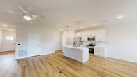 Located at 7231 Weymouth in Perrysburg, Ohio, this well-designed single-floor home offers two bedrooms and two bathrooms with a thoughtful, modern layout. The open-concept kitchen and living area serves as the heart of the home, featuring warm luxury vinyl plank flooring, recessed lighting, and a ceiling fan. The kitchen is outfitted with crisp white shaker cabinetry, a classic subway tile backsplash, stainless steel appliances including a French door refrigerator, electric range, and microwave, all centered around a large white island with an undermount sink and stylish pendant lighting. The spacious living area flows naturally from the kitchen, creating an ideal space for daily living and entertaining. The primary bedroom is a comfortable retreat with its own closet access, while a generously sized walk-in closet with wire shelving and basket storage provides excellent organization. The second bedroom features soft carpet flooring and a bright window overlooking the neighborhood. Both bathrooms are finished in a clean, neutral palette with white cabinetry, light countertops, and tub-shower combinations. Three closets throughout the home, along with a dedicated hallway, ensure ample storage. The overall aesthetic is fresh and contemporary, with a consistent use of light tones and quality finishes.